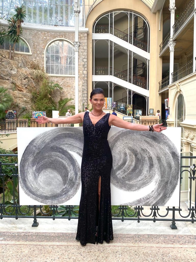 Agnieszka Victoria, contemporary abstract artist, presenting her monochrome abstract painting at an art exhibition